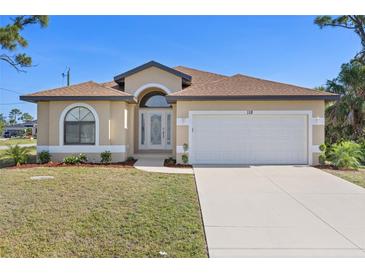 Inviting single-story home with a well-manicured lawn, arched windows, and a two-car garage at 118 Naomi Pl, Rotonda West, FL 33947