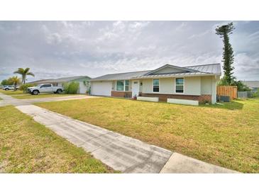 Charming one-story home with a metal roof, a well-manicured lawn and an attached one-car garage at 13495 Newport Ave, Port Charlotte, FL 33981