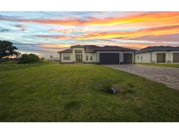 Beautiful single-story home with manicured lawn and a three-car garage under a colorful sunset at 15 Tournament Rd, Rotonda West, FL 33947