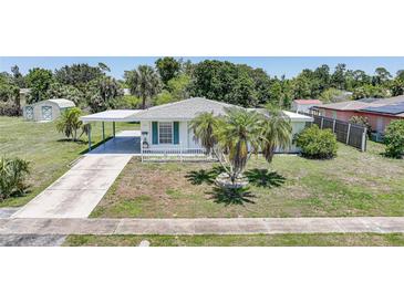 Charming single story home with attached carport, well-manicured lawn, and mature landscaping at 1596 Hayworth Rd, Port Charlotte, FL 33952