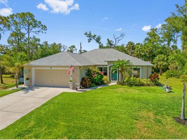 Charming single-story home featuring a well-manicured lawn, attached garage, and tasteful landscaping at 17396 Cox Ave, Port Charlotte, FL 33948
