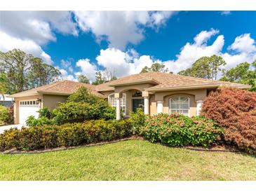 Charming one-story home with a well-maintained lawn, lush landscaping and an attached garage at 4443 Abcor Rd, North Port, FL 34286