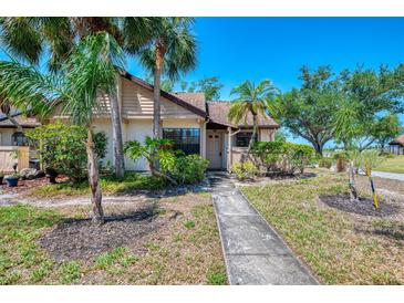 Charming home exterior with lush tropical landscaping and mature trees in a sunny setting at 5641 Mashie Cir, North Port, FL 34287