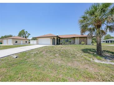 Charming single-story home featuring an attached garage, concrete drive and mature palm trees at 1039 Marlene St, Port Charlotte, FL 33952