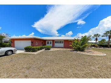 Charming coral home with a white metal roof, lush landscaping, and a welcoming front entrance at 190 Casa Ln, Punta Gorda, FL 33950