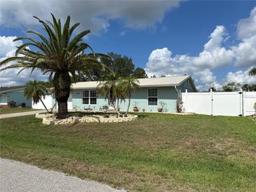 Charming single-story home featuring a landscaped front yard with a majestic palm tree and white picket fence at 4089 Yucatan Cir, Port Charlotte, FL 33948