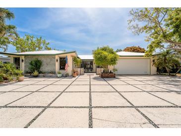 Charming single-story home featuring an expansive paved driveway and lush tropical landscaping at 155 Donna Ct, Punta Gorda, FL 33950
