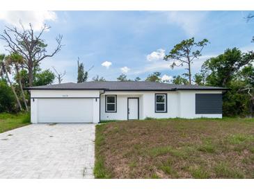 Charming single-story home with a modern white exterior and a well-manicured front lawn at 16218 Chamberlain Blvd, Port Charlotte, FL 33954