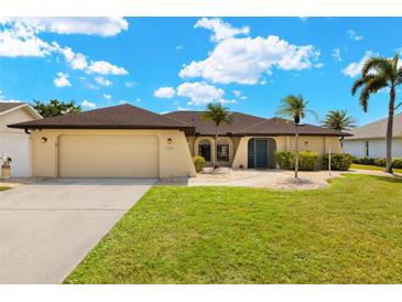Inviting single-story home featuring a manicured lawn, palm trees, and a neutral-toned exterior paint at 2152 Taiwan Ct, Punta Gorda, FL 33983