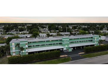 Sunrise Towers complex showing covered parking, green facade, and neatly trimmed hedges at 2486 Caring Way # 14A, Port Charlotte, FL 33952