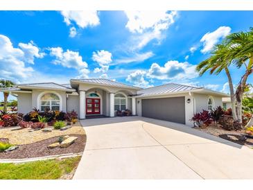 Beautiful single-story home with a red front door, gray siding, landscaped yard, and a spacious driveway at 4216 Bur St, Port Charlotte, FL 33948