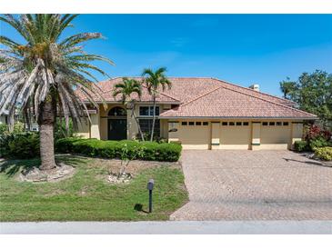 Charming single-story home with a brick driveway, three-car garage, and lush landscaping at 5023 Key Largo Dr, Punta Gorda, FL 33950