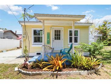 Charming yellow home featuring a cozy front porch with a welcome sign and a small, landscaped garden at 233 N New York Ave, Englewood, FL 34223