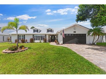 Charming single-story home featuring a well-manicured lawn, brick driveway, and a two-car garage at 425 Corrientes Cir, Punta Gorda, FL 33983