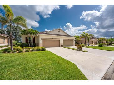 Beautiful townhome with a two-car garage, lush lawn, and tropical landscaping at 8866 Tuscany Isles Dr, Punta Gorda, FL 33950