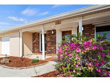 Charming brick home featuring a covered entrance, columns, and vibrant pink azalea bushes at 125 Small Se St, Port Charlotte, FL 33952