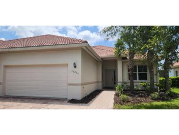 Charming single-story home with a tile roof, manicured landscaping, and an attached two-car garage at 13256 Creekside Ln, Port Charlotte, FL 33953