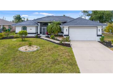 Well-maintained home with a landscaped front yard and a spacious driveway leading to an attached two-car garage at 15890 Viscount Cir, Port Charlotte, FL 33981
