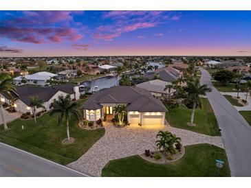 Waterfront home boasts lush landscaping, paver driveway and a three-car garage at dusk at 1932 Los Alamos Dr, Punta Gorda, FL 33950