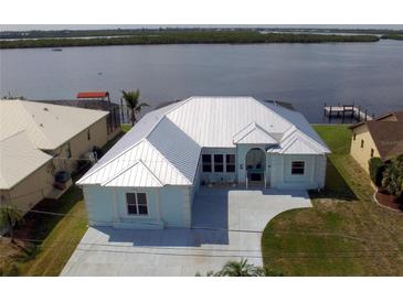 Waterfront property with a freshly painted exterior, metal roof, and well-maintained landscaping at 3772 Peace River Dr, Punta Gorda, FL 33983