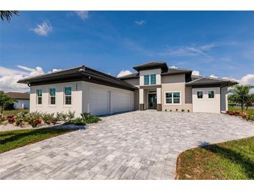 Stunning modern home featuring a paver driveway, attached garage, and well-manicured landscaping at 5061 Collingswood Blvd, Port Charlotte, FL 33948