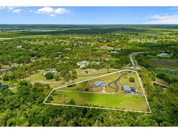 Beautiful aerial view of a sprawling home with a pool and guesthouse surrounded by lush greenery and defined property lines at 5600 Blackjack S Ct, Punta Gorda, FL 33982