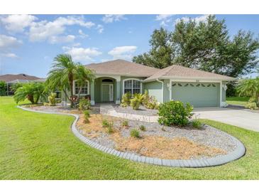 Charming single-story home with lush landscaping, palm trees, and a well-maintained lawn under a partly cloudy sky at 7101 Dogwood Ct, North Port, FL 34287