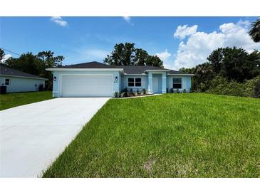 Charming light blue single-story home featuring a lush green lawn and a two-car garage at 8667 Lisa Blvd, North Port, FL 34288