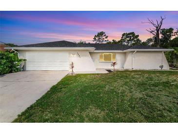 Charming single-story home featuring a two-car garage, manicured lawn, and freshly painted exterior at sunset at 1231 Beacon Dr, Port Charlotte, FL 33952