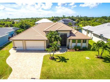 Beautiful home featuring a tile roof, an attached two-car garage, manicured landscaping, and a paved driveway at 13830 Begonia Cir, Port Charlotte, FL 33981