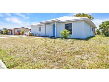 Charming light blue single-story home with a well-maintained lawn and a bright blue front door at 22299 Laramore Ave, Port Charlotte, FL 33952