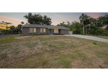 Charming single-story home featuring an attached garage, well-maintained front yard, and a welcoming blue front door at 23165 Glen Ave, Punta Gorda, FL 33980