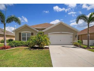 Charming single-story home featuring a well-manicured lawn, mature palm trees, and a two-car garage at 25008 Lalique Pl, Punta Gorda, FL 33950