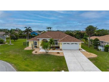 Inviting single-story home with a well-manicured lawn, palm trees, and a spacious driveway leading to an attached two-car garage at 7512 Pon Kan, Punta Gorda, FL 33955