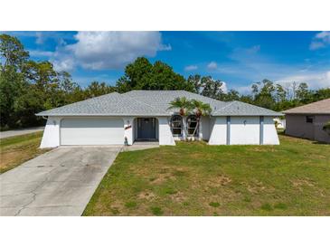 Charming single-story home featuring a two-car garage, and tropical landscaping in a well-maintained lawn at 891 Bayard St, Port Charlotte, FL 33948