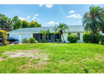 Charming single story home featuring an attached two car garage and tropical landscaping at 18585 Klingler Cir, Port Charlotte, FL 33948