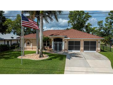 Beautiful single-story home with a well-manicured lawn, tile roof, and American flag at 2387 Nuremberg Blvd, Punta Gorda, FL 33983