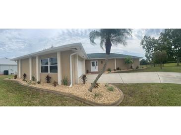 Charming single-story home features a well-manicured lawn, palm tree, and a double-door entryway at 26129 Madras Ct, Punta Gorda, FL 33983
