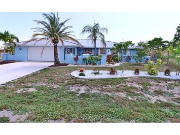 Charming blue single-story home featuring a metal roof, lush landscaping, and a well-manicured lawn at 107 Sinclair Se St, Port Charlotte, FL 33952