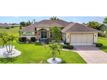 Well-maintained home boasts manicured lawn, decorative landscaping, and a brick driveway leading to an attached two-car garage at 1499 Nuremberg Blvd, Punta Gorda, FL 33983