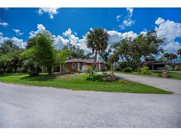Charming single-story home with a well-manicured front yard, mature trees, and a circular driveway at 3960 Magara Ter, North Port, FL 34287