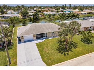 Inviting waterfront home with lush landscaping, screened in porch, and a long concrete driveway at 444 Edgewood Rd, Venice, FL 34293