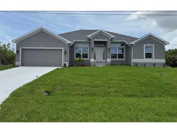Charming gray single-story home with well-manicured lawn and attached two-car garage at 10023 Greetings St, Port Charlotte, FL 33981