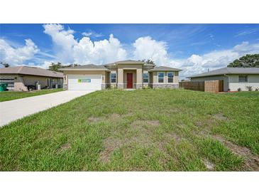 A single-Gathering home featuring a well-maintained lawn, neutral tones, and a red entry door at 1057 Presque Isle Dr, Port Charlotte, FL 33952