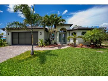 Charming home with a well-manicured lawn, brick driveway, and tropical landscaping at 13471 Chenille Dr, Port Charlotte, FL 33981