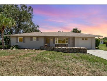 Charming single-story home with a well-maintained lawn and rock border at sunset at 18178 Wolbrette Cir, Port Charlotte, FL 33948