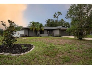 Charming one-story home with mature landscaping, featuring a well-maintained lawn and palm trees at 21220 Pemberton Ave, Port Charlotte, FL 33952