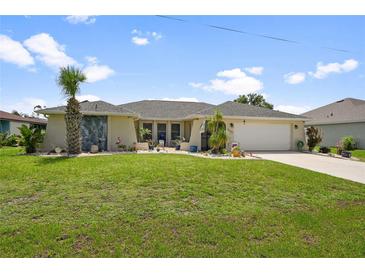 Charming single-story home featuring a well-manicured lawn and tropical landscaping at 26125 Copiapo Cir, Punta Gorda, FL 33983