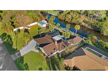 Aerial view of home featuring a private canal, screened pool, and lush landscaping at 372 Cory St, Port Charlotte, FL 33953