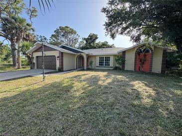 Charming single-story home with a well-manicured lawn, arched entryways, and attached two-car garage at 726 Chevy Chase St, Port Charlotte, FL 33948